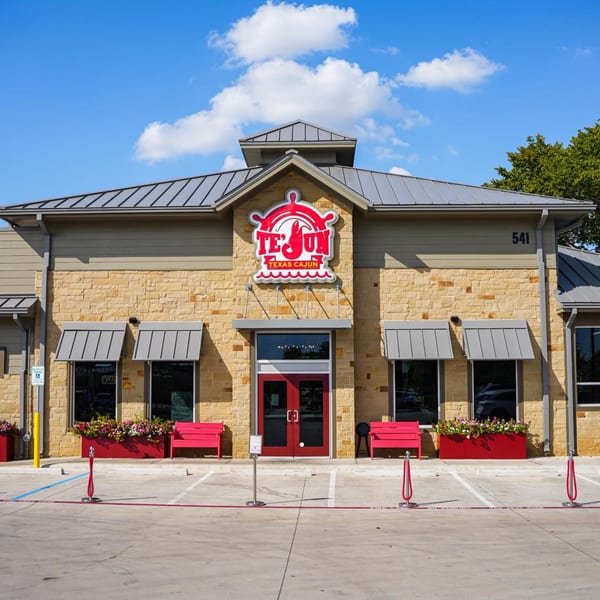 The Te'Jun Texas Cajun restaurant exterior with a red logo, red doors, and red benches.