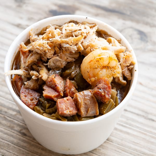 Close-up of a white bowl filled with gumbo, topped with shrimp, sausage, and crab meat.